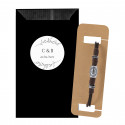 Pulseira de couro e adornos prateados em envelope preto com adesivo personalizado de iniciais para eventos